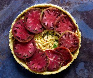 Layer-thick-slices-of-heirloom-tomatoes-atop-prepared-ackee