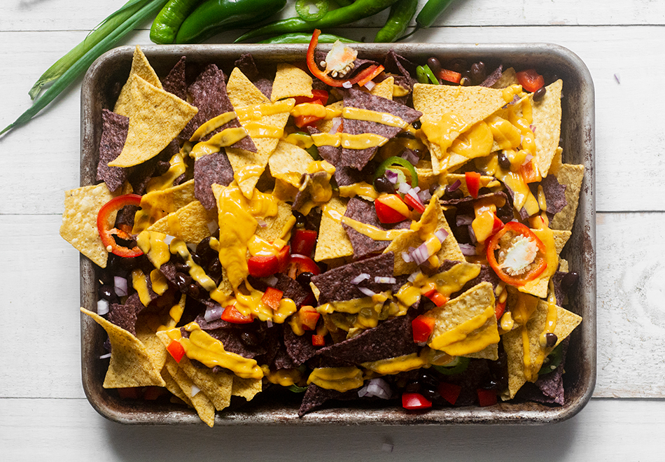 step-three-continue-layering-the-nachos-beans-addins-and-cheese-sauce